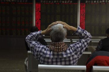 An investor reacts near boards displaying stock market prices in Beij