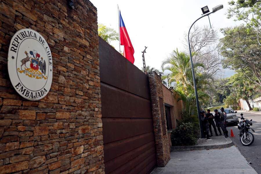 Police officers stand outside the residence of the Chilean ambassador in Caracas