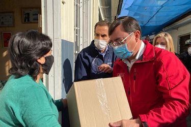 Felipe Guevara y Felipe Alessandri entregan una caja de mercadería del Gobierno.