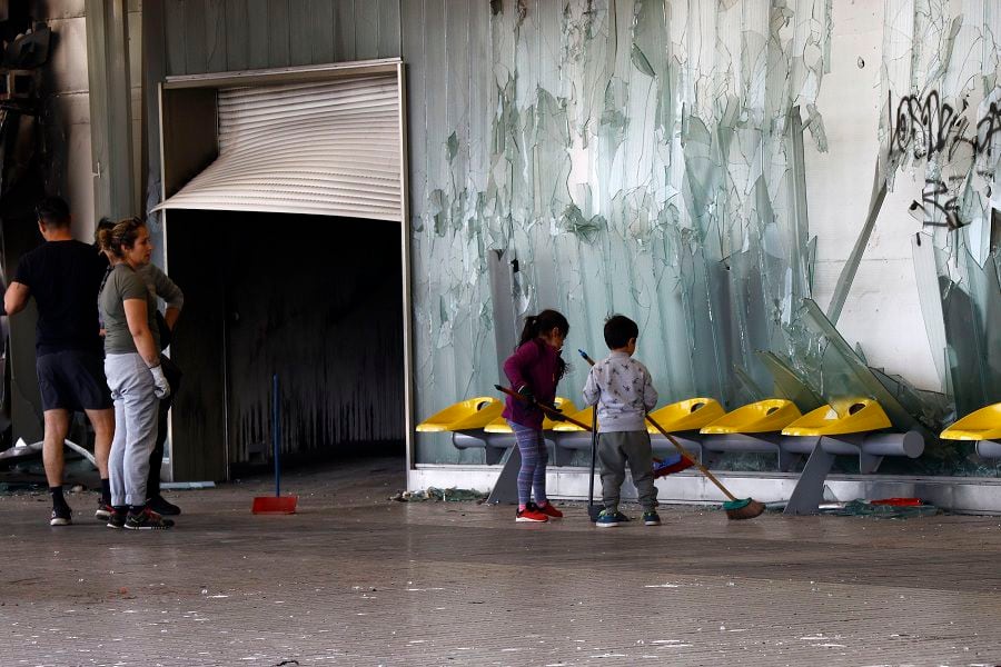 20 de Octubre de 2019. Una familia junto a sus hijos limpia los destrozos en la estación Del Sol en Maipú, luego de que una turba la destruyera. Foto: Mario Dávila / AgenciaUno.
