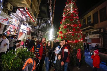 Syrians pose for a picture as they gather around a Christmas tree in