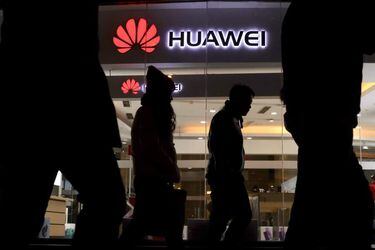 Pedestrians walk past a Huawei retail shop in Beijing Thursday, Dec.