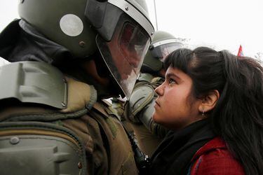 A demonstrator looks at a riot policeman during a protest marking the country's 1973 military coup in Santiago, Chile