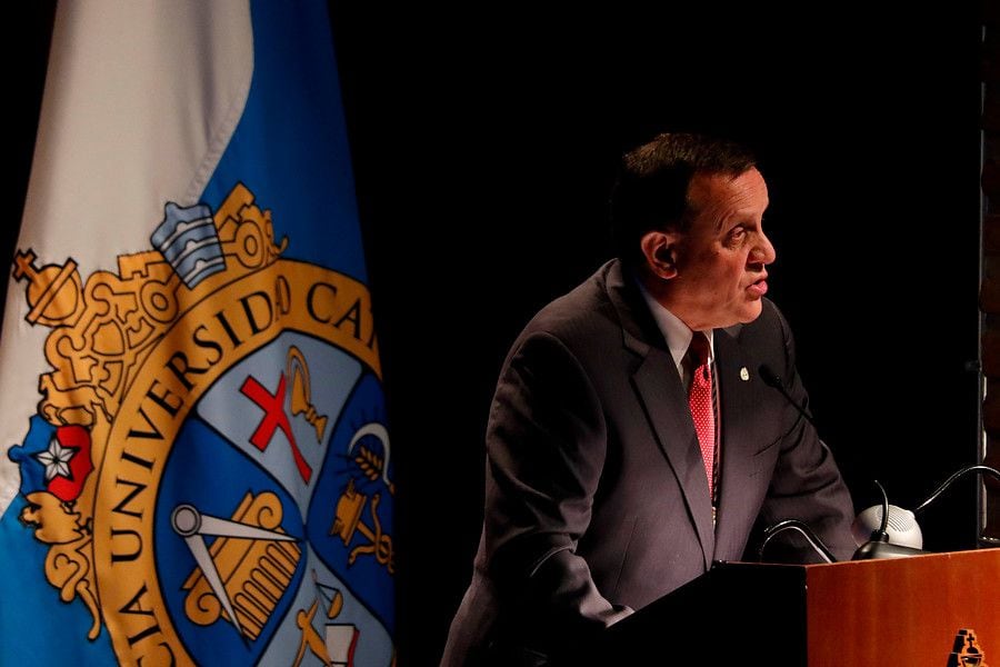 Ignacio Sánchez, rector de la PUC junto al emblema principal. Foto referencial.