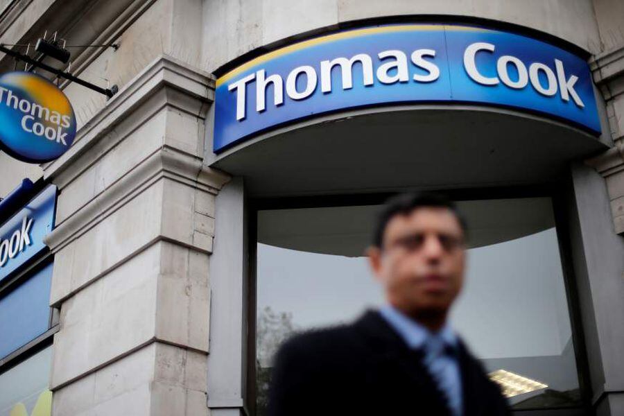 FILE PHOTO: A pedestrian walks past a Thomas Cook shop in central London