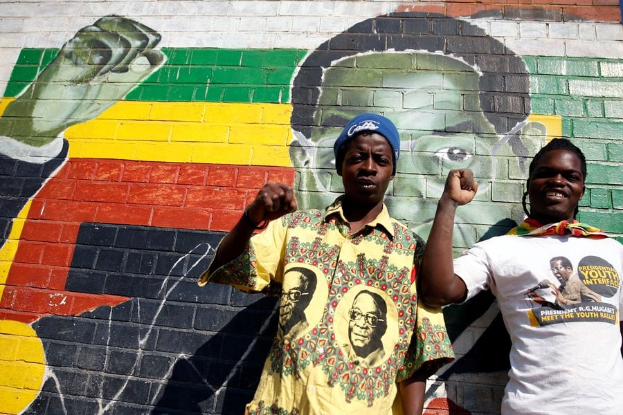 Youths stand besides a mural depicting Zimbabwe's former President Robert Mugabe after hearing the news of his death, in Mbare in the capital Harare