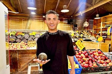 Felipe Flores exhibe una de las paltas que vende, en un supermercado.