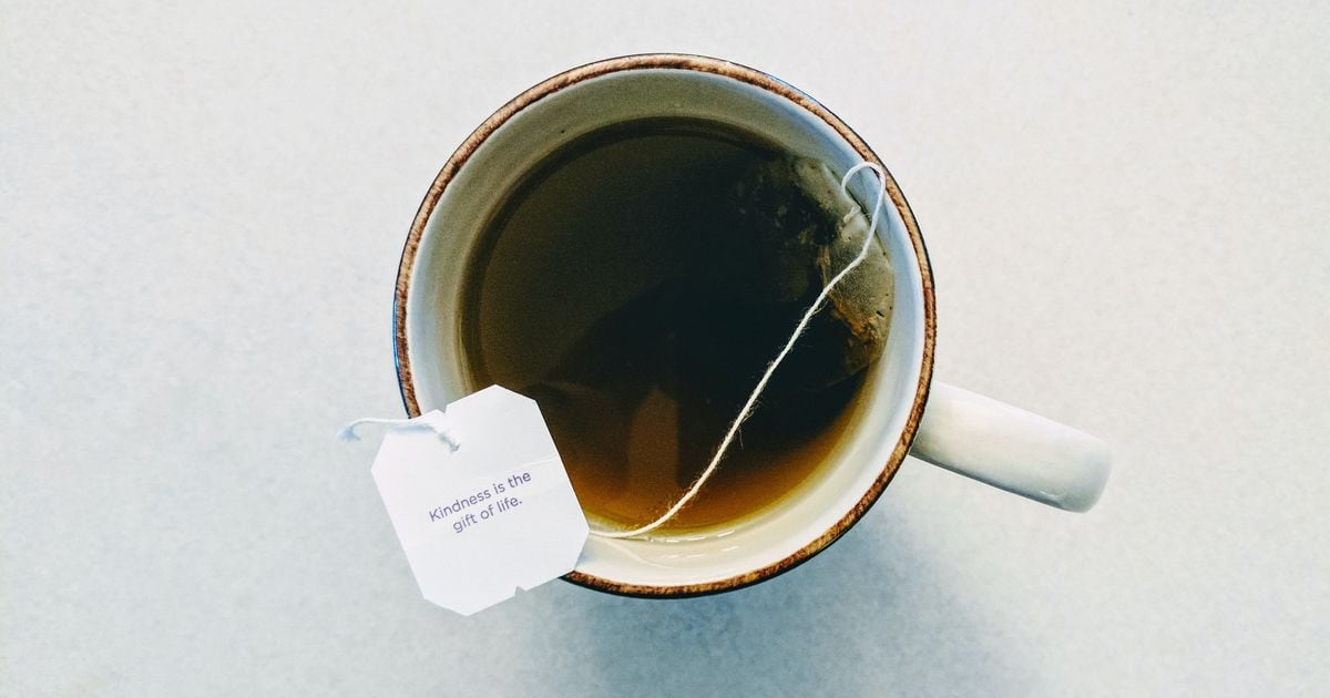 Una taza de té caliente con hojas y bolsitas de té.