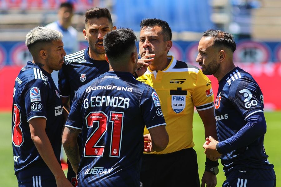 El árbitro Julio Bascuñán recibe los reclamos de los jugadores de la U, en el clásico universitario.