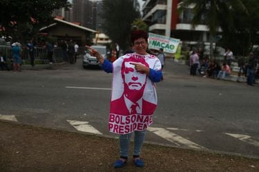 A supporter of Brazil's new president-elect, Jair Bolsonaro, wearing a piece of cloth with an image of his face, gestures outside his condominium at Barra da Tijuca neighborhood in Rio de Janeiro