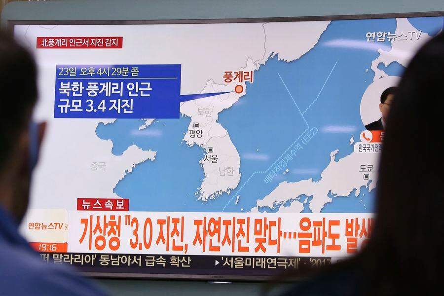 People watch a TV news program reporting North Korea's earthquake