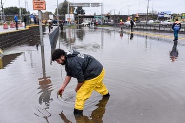 Personas trabajan en el drenaje de la inundación en calle 21 de Mayo, en  Concepción, Región del Biobío, tras las lluvias.