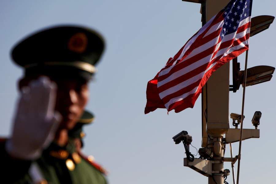 FILE PHOTO: A paramilitary policeman gestures under a pole with security cameras, U.S. and China's flags near the Forbidden City ahead of the visit by U.S. President Donald Trump to Beijing