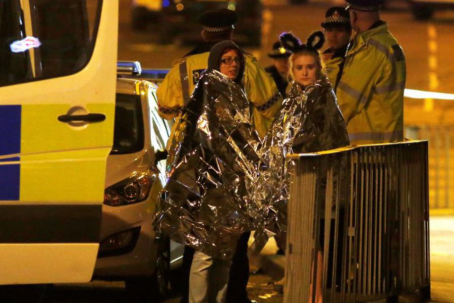 Two women wrapped in thermal blankets stand near the Manchester Arena, where U.S. singer Ariana Grande had been performing, in Manchester, northern England, Britain