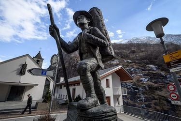 A man walks past a statue of a local smuggler in southern Swiss villa