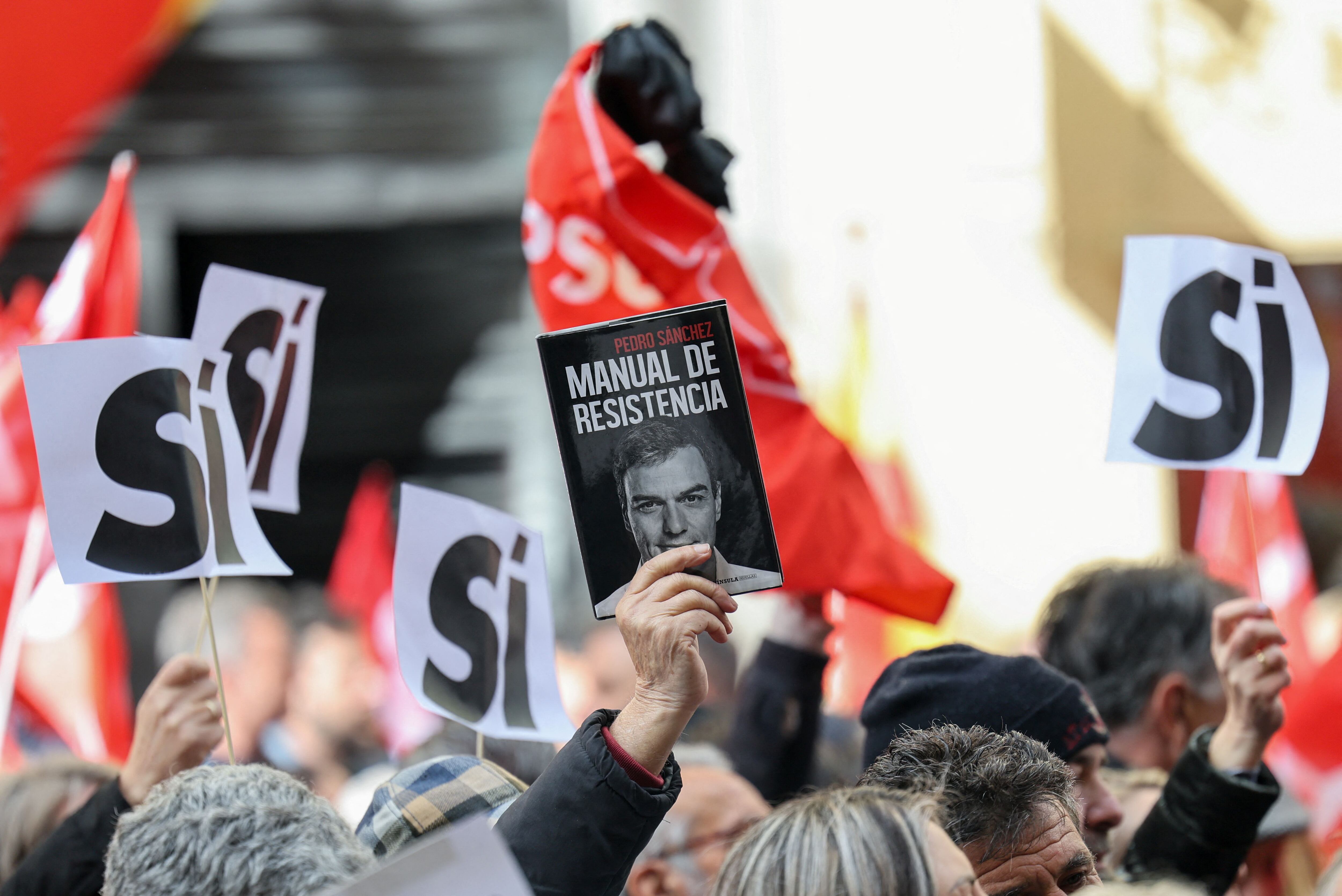 Una persona sostiene una copia del libro "Manual de resistencia" de  Pedro Sánchez, mientras la gente se reúne frente a la sede del PSOE para mostrar su apoyo al jefe de gobierno español, en Madrid, el 27 de abril de 2024. Фота: Reuters