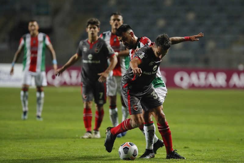 Misael Dávila disputa un balón con un jugador rival, durante el duelo entre Palestino y Newell's. FOTO: Agencia Uno.
