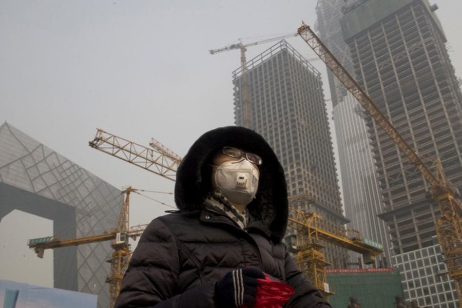 A woman wears a mask as she walks past a construction site as smog co