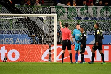 A referee (L) points to a penalty kick after speaking with the video