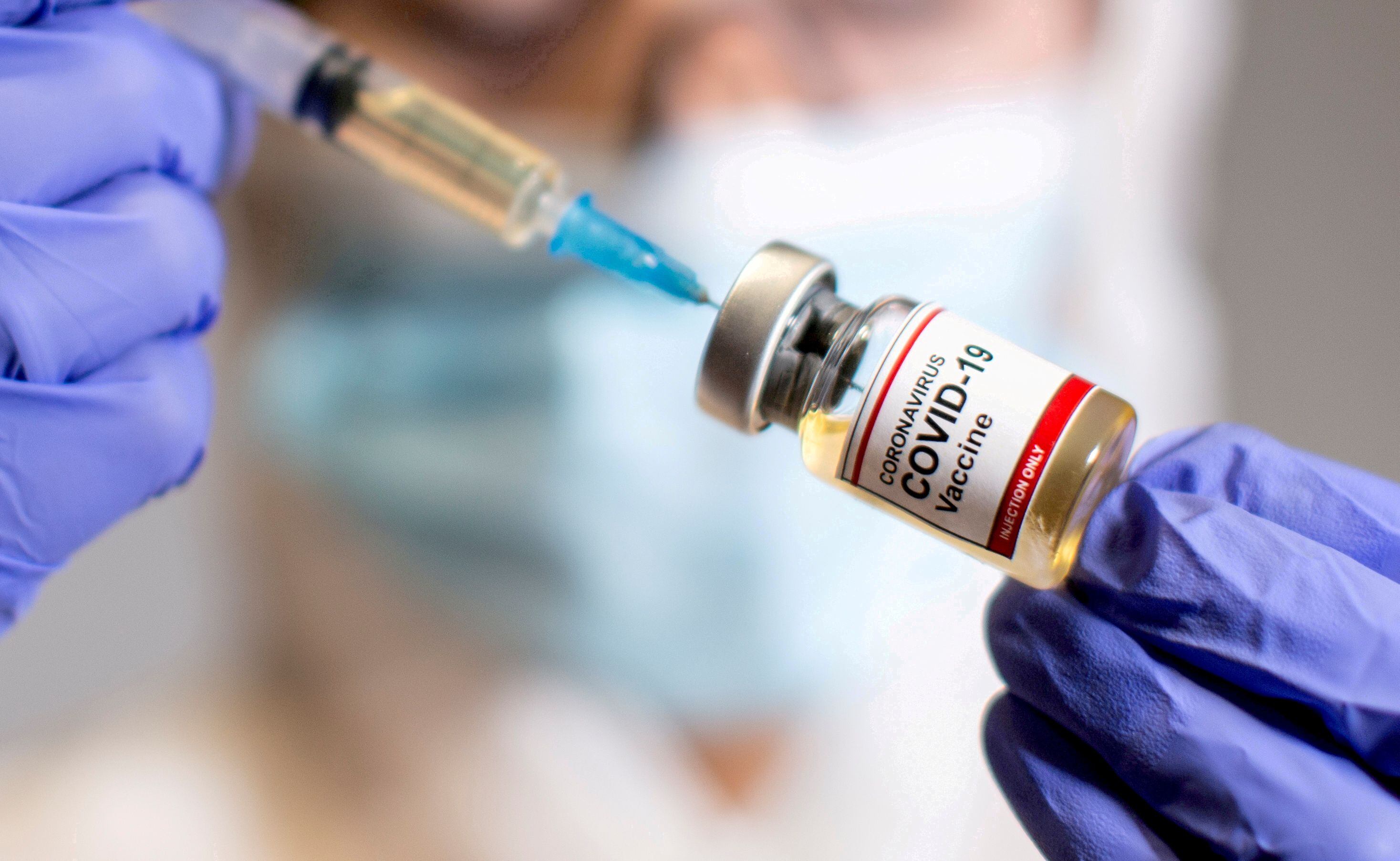 FOTO DE ARCHIVO: Una mujer sostiene un pequeño frasco etiquetado con una etiqueta de "Vacuna contra el Coronavirus COVID-19" y una jeringuilla médica en esta ilustración