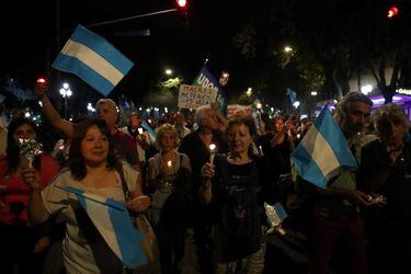 Demonstrators hold candles and wave Argentine national flags during a protest against utility rate hikes in Buenos Aires