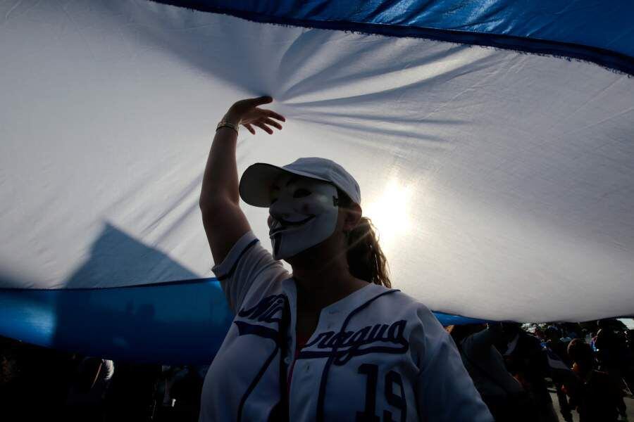 A masked demonstrator holds a big national flag during a protest against Nicaraguan President Daniel Ortega's government in Managua