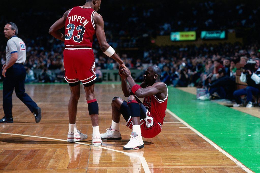 BOSTON - 1990:  Scottie Pippen #33 helps Michael Jordan #23 of the Chicago Bulls up from the floor against the Boston Celtics during a game played in 1990 at the Boston Garden in Boston, Massachusetts. NOTE TO USER: User expressly acknowledges and agrees that, by downloading and or using this photograph, User is consenting to the terms and conditions of the Getty Images License Agreement. Mandatory Copyright Notice: Copyright 1990 NBAE (Photo by Dick Raphael/NBAE via Getty Images)