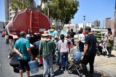 Vecinos de Antofagasta llenando bidones de agua desde camiones por el corte de suministro que afecta a 60 mil clientes desde el domingo ante falla en una planta desaladora de la ciudad.