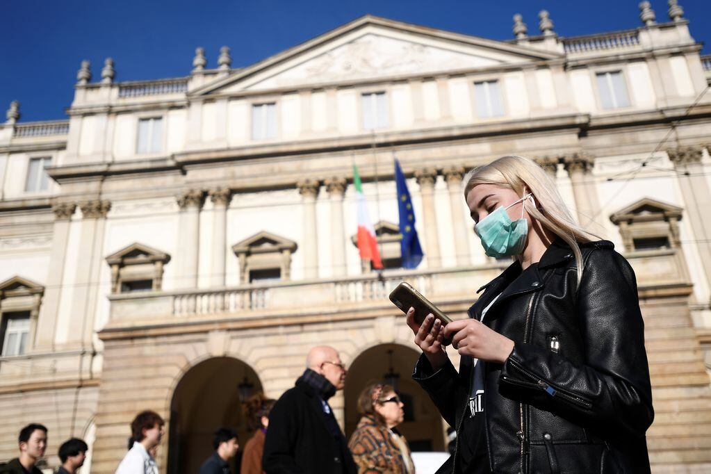 A woman wearing a face mask checks her phone outside the Teatro alla Scala, closed by authorities due to a coronavirus outbreak, in Milan, Italy February 24, 2020. REUTERS/Flavio Lo Scalzo