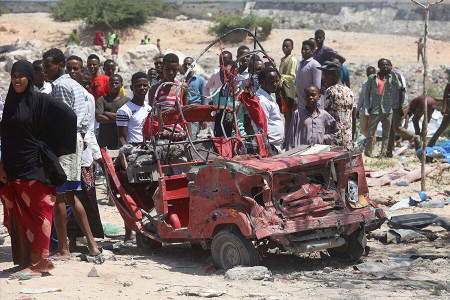 Civilians look at the remain of a rickshaw destroyed at the site of a blast in the district office of Hawlwadag in Mogadishu