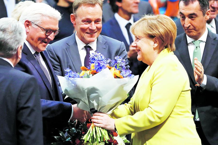 German Chancellor Angela Merkel (R) hands over flowers to new elected