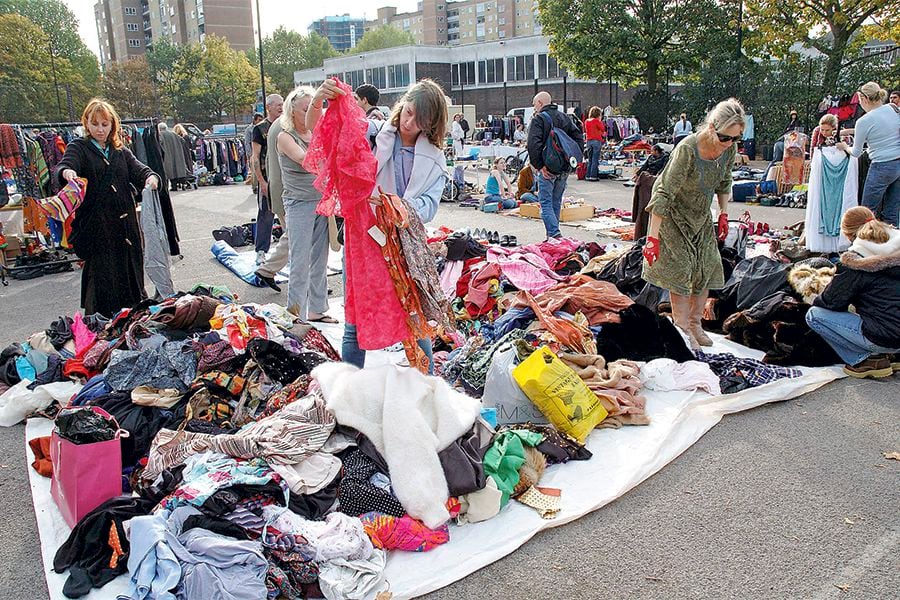 People going through piles of clothes looking for bargains at a boot sale in South london