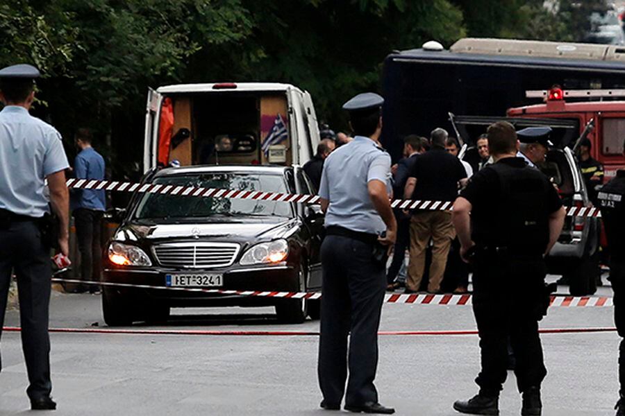 Police secure the area around the car of former Greek prime minister and former central bank chief Lucas Papademos following the detonation of an envelope injuring him and his driver, in Athens
