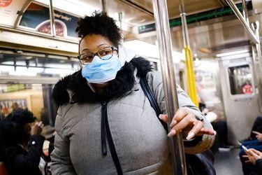 Una mujer en el metro de nueva york con mascarilla