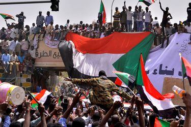 Sudanese demonstrators carry a military officer as they chant slogans and carry their national flags outside Defence Ministry in Khartoum