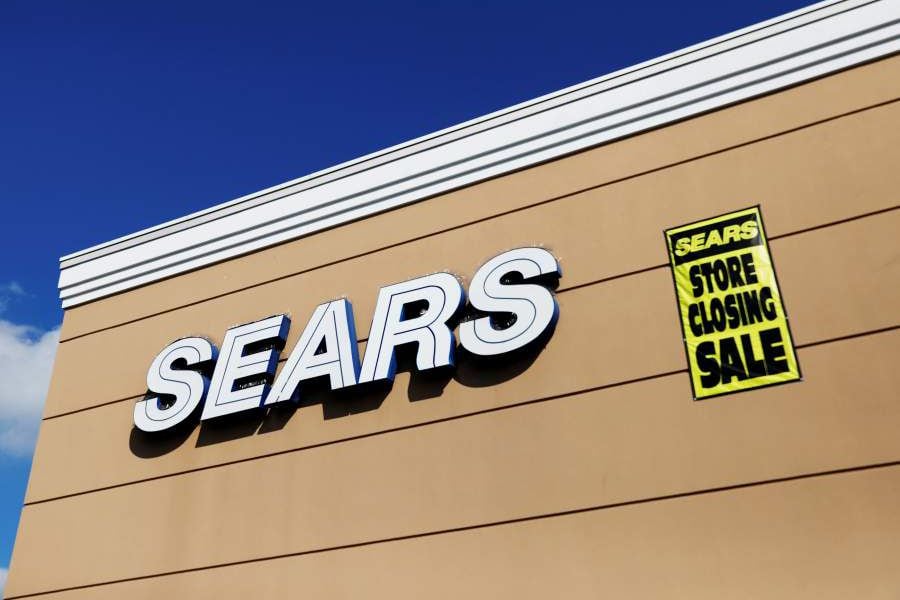 FILE PHOTO: A store closing sale sign is posted next to a Sears logo in New Hyde Park, New York