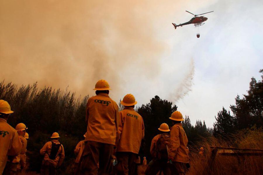 A helicopter dumps water during a forest fire in the town of Empedrado in the Maule region, south of Chile