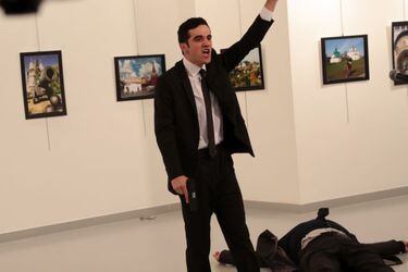 A man gestures near to the body of a man at a photo gallery in Ankara