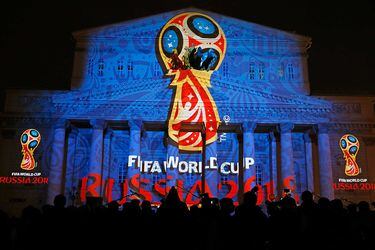 Journalists look at a light installation showing the official logotype of the 2018 FIFA World Cup during its unveiling ceremony at the Bolshoi Theater building in Moscow