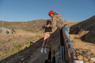 A migrant from Honduras pass a child to her father after he jumped th