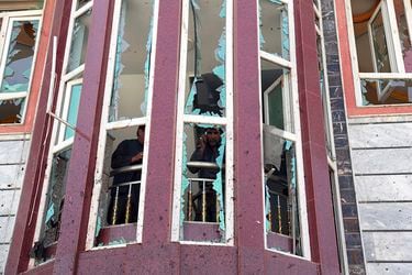 Afghans are seen through shattered windows of a voter registration ce