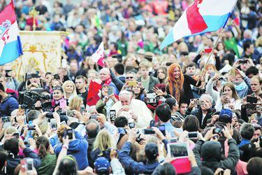 Pope Francis kisses a baby as Croatian flags are waved by pilgrims at