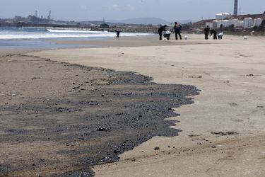Trabajadores de una empresa particular limpian la playa de Loncura, afectada por un derrame de combustible en la bahía de Quintero.