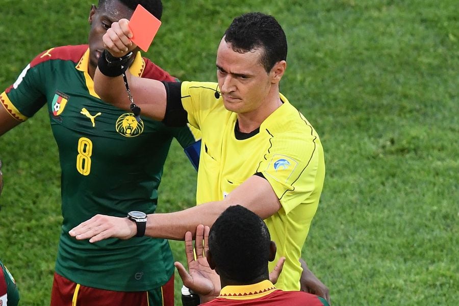 Colombian referee Wilmar Roldan (R) gives a red card to Cameroon's de