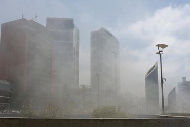 Smoke from Larcomar mall partially obscures buildings nearby, including JW Marriott Hotel Lima, during a fire at the mall where at least three people died, according to the fire department, in Lima