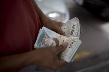 A employee accounts bolivar's bills at a gas station in Caracas