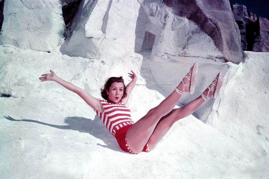 1950's A picture of American Hollywood film actress most famous for her roles in musical-dancing films Debbie Reynolds, posing with her legs in the air on some rocks.
