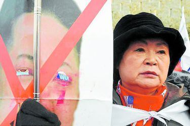 An anti-North Korea protester holds a damaged picture of North Korean