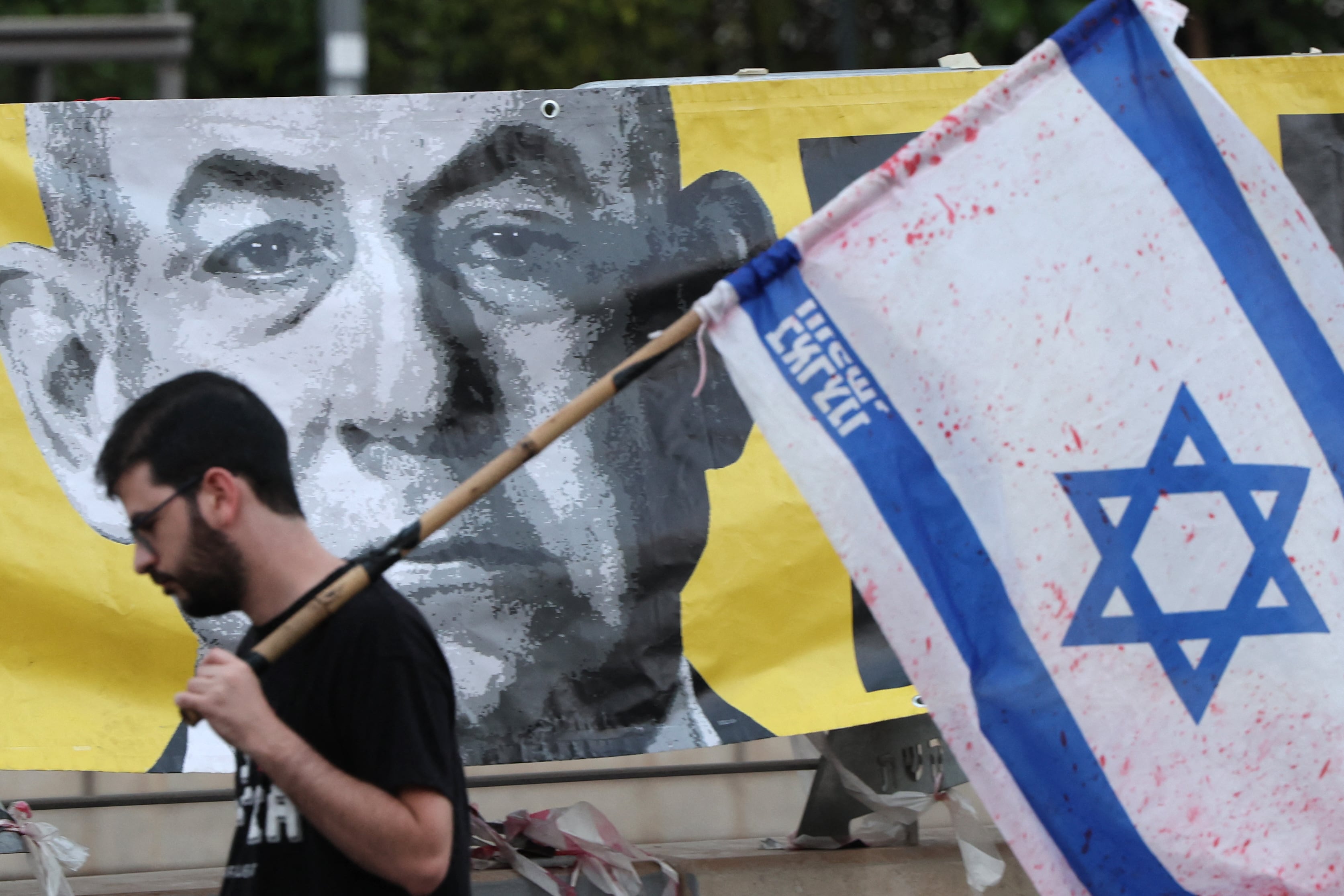 Un manifestante con la bandera israelí pasa junto a un retrato del primer ministro Benjamin Netanyahu durante una protesta antigubernamental. Foto: Archivo