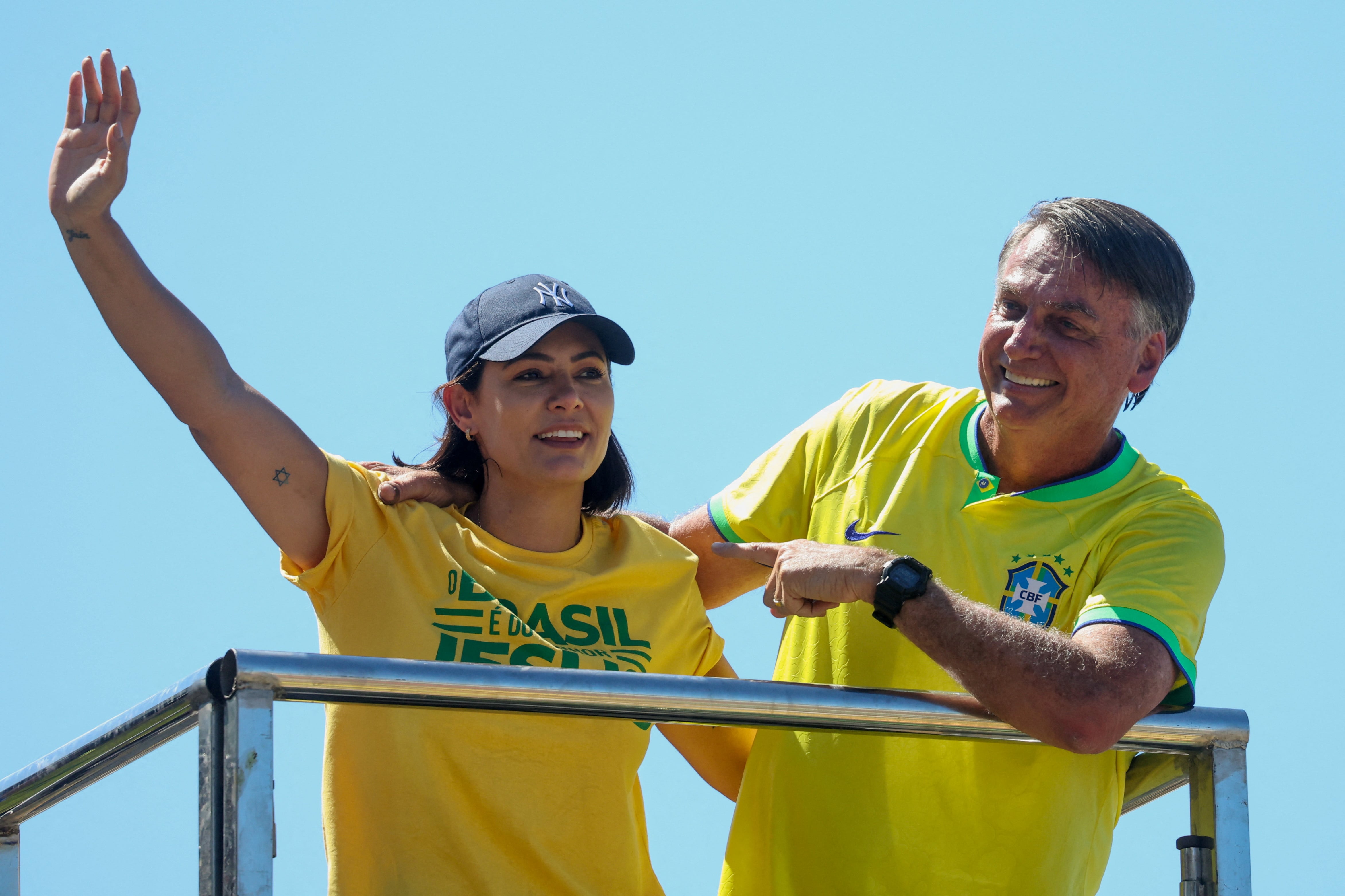 El expresidente de Brasil, Jair Bolsonaro, señala a su esposa, Michelle Bolsonaro, mientras asisten a una manifestación a la que convocó a sus seguidores en la playa de Copacabana, en Río de Janeiro, el 21 de abril de 2024.